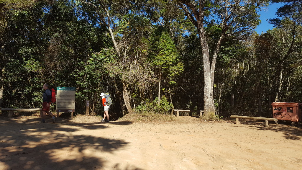 Estacionamento do Bauzinho, na frente da Michelle tem a trilha principal que vai direto ao cume do Bauzinho, a direita na altura do lixo tem uma trilha menor que leva a base das vias.